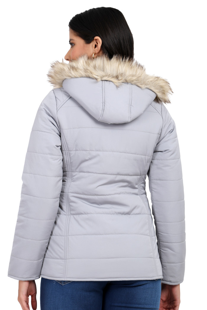 A back pose of a standing woman, wearing Trufit’s grey matte quilted jacket with a detachable hood and blue jeans.